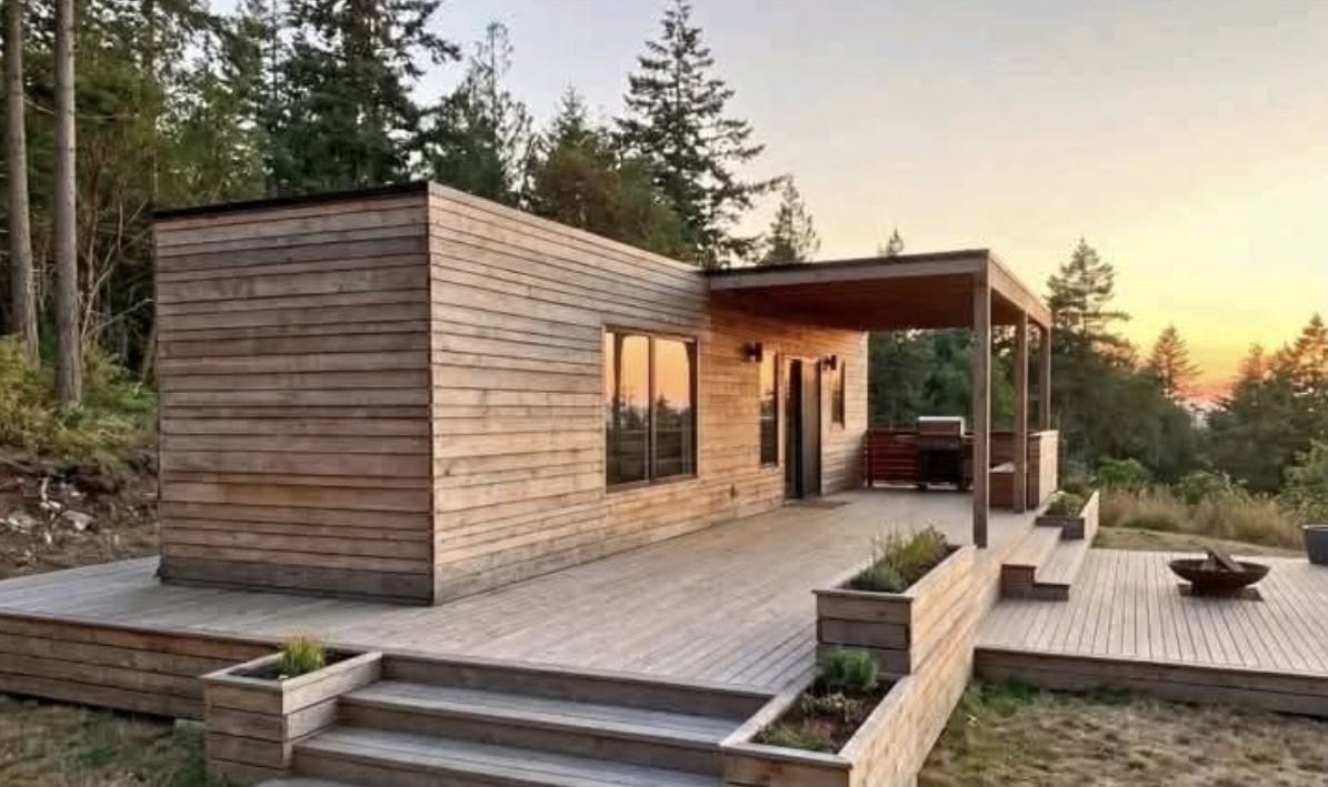 The Cedar wood-clad container home at sunset with a covered deck