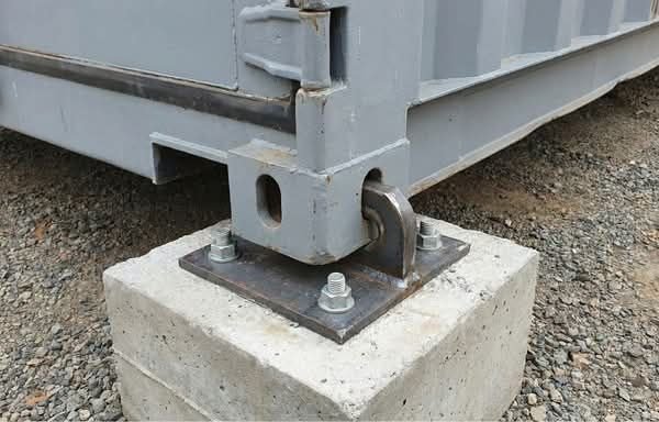 Container corner casting anchored to a concrete foundation pier